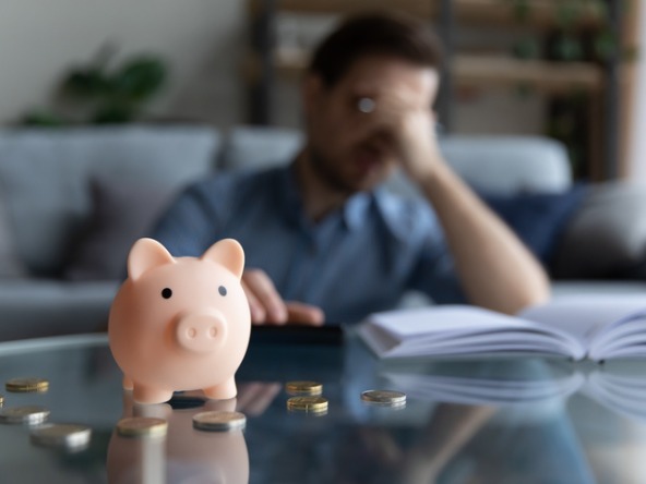 Piggy bank and money, with man worried in the background